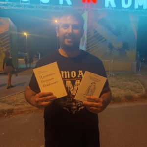 Photo d'un lecteur devant le festival rock in roma avec en main le livre de Tessy Oudèna, mon nom de rue est personne paru chez courgette editions et le livre Désenfantée, Déterminée, Déniaisée de Cindy Vandermeulen paru chez Abrapalabra Editions.